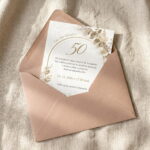 Pozvánka na oslavu 50 rokov vložená v jemnej ružovej obálke na textilnom podklade